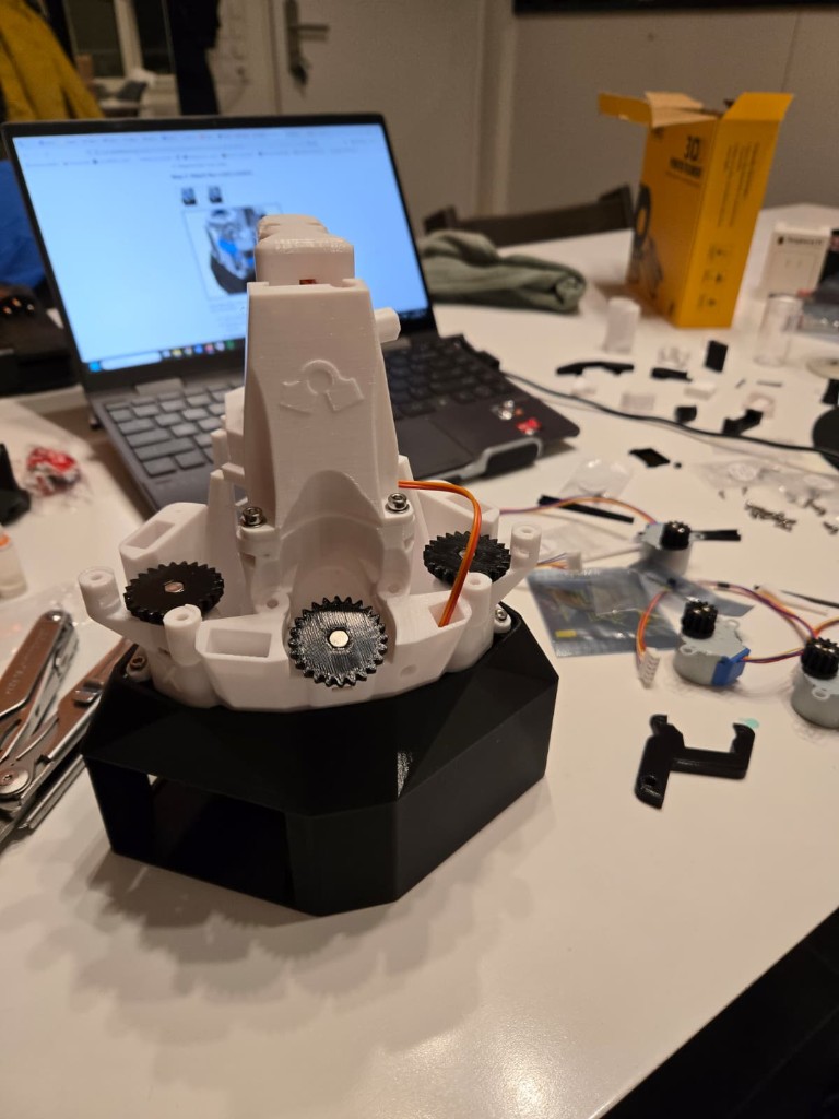 Partially assembled 3D-printed open microscope with gearing on a workbench